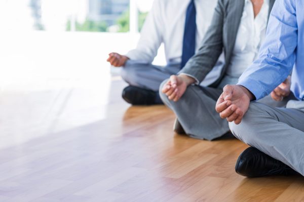Close up view of business people doing yoga in office
