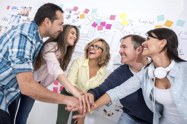 Group of people with hands together working at a creative office - teamwork concepts